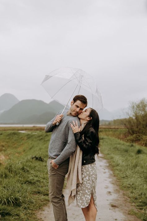 Couple getting cozy in the rain with a clear umbrella while she is kissing him on the cheek. Vancouver Photoshoot, Rainy Photoshoot, Rainy Engagement Photos, Rainy Wedding Photos, Rainy Photos, Rainy Day Photos, Photo Posing, Fall Engagement Pictures, Rain Photo