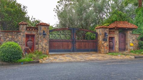 Spanish inspired driveway gate and pedestrian door beautifully constructed in Rancho Santa Fe, CA. Gated Home Exterior, Hacienda Entrance Gates, Mediterranean Gate Entrance, Spanish Fences And Gates, Gated Entrance Landscaping, Hacienda Driveway, Wooden Gate Designs Driveways, House Gate Entrance, Ranch Gates Entrance Ideas