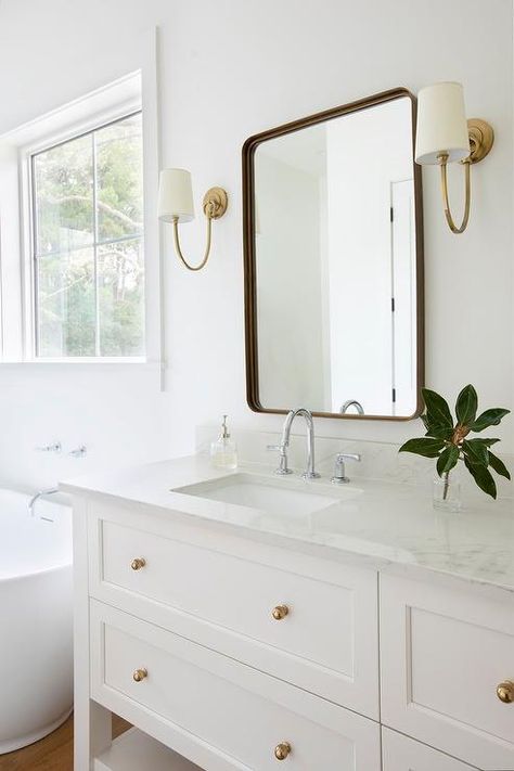 White Vanities With Gold Hardware, White Vanity Brass Fixtures, Antique Brass Bathroom Sconces, Bathroom Decor Chrome Fixtures, Light Blue And Brass Bathroom, Beige Sink Bathroom Ideas, White Bathroom Vanity With Wainscoting, White Bathroom With Silver Fixtures, Brass Chrome Bathroom