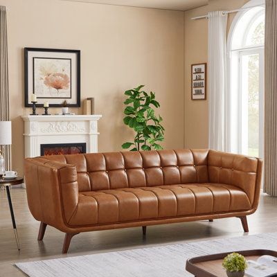 Anchor your space in mid-century modern style with the Mastin 84" leather sofa. Combining durable, top-quality craftsmanship and high-density foam this sofa will provide you with great comfort and undoubtedly become the centerpiece of your living room, den, urban loft, condo, or home office. This genuine leather living room couch features a modern chesterfield style inspired by an urban loft lifestyle. These spacey and comfortable top vintage leather couches let you gather everyone into the livi Modern Tufted Sofa, Wood Dining Room Set, Tan Leather Sofas, Affordable Dining Room Sets, Leather Sofa Couch, Genuine Leather Sofa, Mod Furniture, Comfortable Dining Chairs, Space Apartments