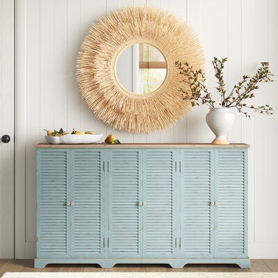 This sideboard showcases a distressed sea green finish that creates a coastal farmhouse accent in your dining room or living room. It's made from solid fir and engineered wood with a natural-finished top for a breezy hint of contrast. The three double-door cabinets have louvered doors that add eye-catching farmhouse detail and are open to reveal two fixed shelves in each where you can keep your server or barware. Plus, this buffet table arrives fully assembled. | Sand & Stable™ Ocala 63" Wide Wo Coastal Mud Rooms, Coastal Chic Furniture, Coastal Entry Table Decor, Coastal Cabinet Pulls, Coastal Back Porch, Coastal Media Console, Coastal Buffet Table, Coastal Farmhouse Decor Living Room, Coastal Entry Table