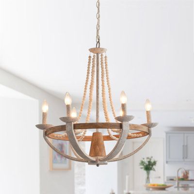 This 6-light wagon wheel chandelier has a pared-down, open frame that makes it casual enough for your rustic dining room table. This fixture is crafted from metal with a gray/antique white finish, and it strikes an empire silhouette with beaded accents for a boho touch and hangs from an adjustable chain. With its open design, this chandelier provides ample illumination to brighten up any room. It creates a warm and inviting atmosphere for the dining room, laundry room, bedroom, hallway, or entry Industrial Style Living Room, Chandelier Wood, Rustic Dining Room Table, Coastal Chandelier, Beaded Candle, Cottage Lighting, Wheel Chandelier, Empire Chandelier, Iron Lamp