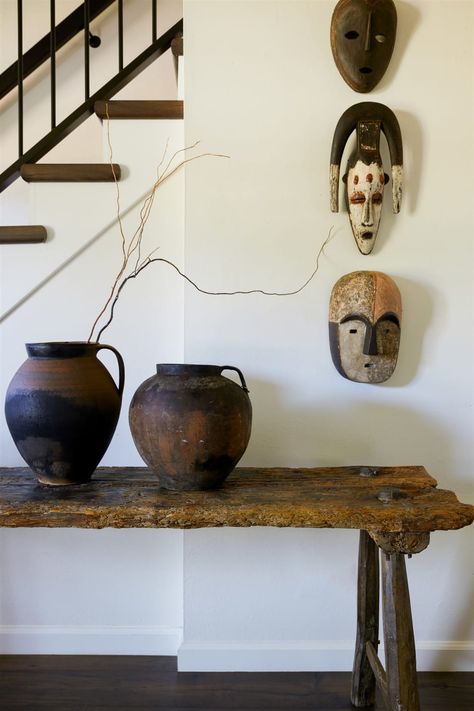 African masks on display in hallway with wooden table and vases. Black Aesthetic House Interior, Lamp Making, African Interior Design, Vintage Headboards, Comfort Art, Large Bouquet, African House, Artistic Ideas, African Interior