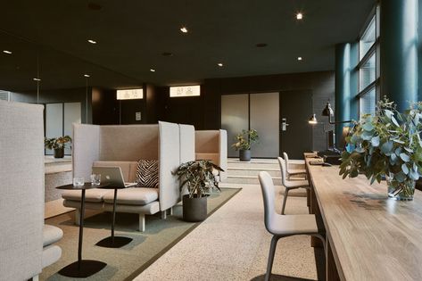 In this work area within a hotel, comfortable booths are paired with small laptop tables, while beside the windows, there's a long wood table. #HotelDesign #Workspace Office Designs, Coworking Space Design, Industrial Office Design, Corporate Office Design, Office Lounge, Office Space Design, 카페 인테리어 디자인, Best Office, Airport Hotel
