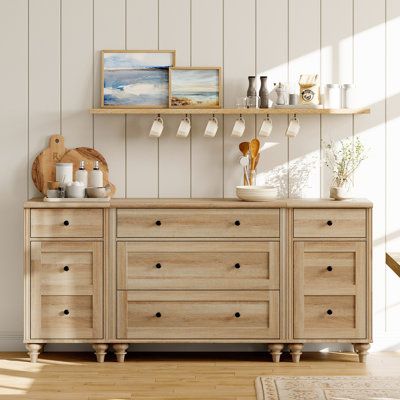 This mid-century-style dresser brings an elegant look to your bedroom with its distressed oak finish and molded detailing. The spacious, low-profile frame is made from a blend of solid and engineered wood. It features multiple drawers that provide ample storage space for your clothes, blankets, and table linens. This versatile dresser is designed to maximize vertical storage in your entryway, dining room, or living room while keeping your essentials in order. The smooth metal slides ensure easy Built In Wall Dresser, Dresser With Floating Shelves Above, Mixed Wood Bedroom Furniture, Dresser And Night Stand Ideas, Dresser Tv Stand Bedroom, Boho Tv Stands Living Rooms, Long Dressers Bedroom, Kitchen Chest Of Drawers, Farmhouse Bedroom Dresser