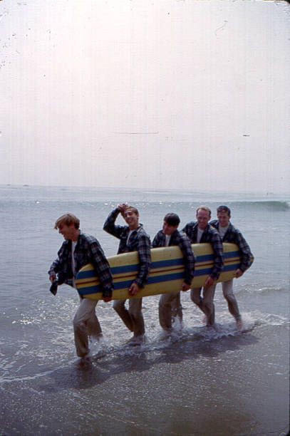 Rock and roll band 'The Beach Boys' walk along the beach holding a surfboard for a portrait session in August 1962 in Los Angeles California Dennis... Los Angeles, The Beach Boys Wallpaper, The Beach Boys Aesthetic, Beach Boys Wallpaper, Surf Rock Aesthetic, The Beach Boys Poster, Beach Boys Aesthetic, Beach Boys Poster, 60s Beach Aesthetic