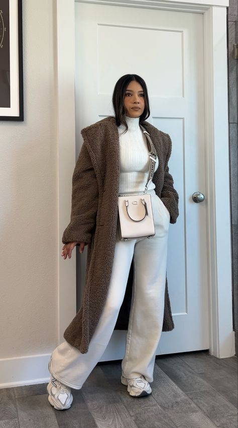 Cream wide leg sweatpants, ribbed turtle neck long sleeve, long teddy brown coat, chunky new balance 9060 sneakers, coach crossbody purse. #fashion #winteroutfit #outfitidea #chicstyle #petitestyle #neutraloutfits Brown Over Coat Outfit, Long Teddy Jacket Outfit, Winter Sneaker Outfit, Casual Outfits With Coat, Coat For Long Dress, Sweats And Coat Outfit, Cream Outfits For Women Casual, Cute Winter Outfits Sweatpants, Styling Wide Leg Sweatpants