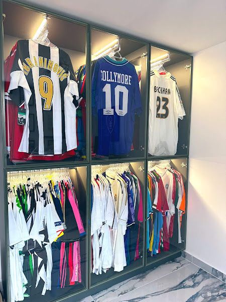 Football Collection Display, Football Shirt Collection Room, Jersey Storage Ideas, Framed Football Shirts, Football Equipment Storage Ideas, Football Bedroom Aesthetic, Soccer Man Cave, Framed Football Jersey, Jersey Collection Display