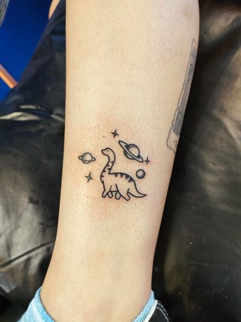 Small dinosaur tattoo in space. T Rex Space Tattoo, Small Matching Space Tattoos, Dino Tattoos Cute, Cute Dino Tattoo Matching, Cute Matching Dinosaur Tattoo, Lil Dinosaur Tattoo, Cute Tattoos Dinosaur, Tattoo Ideas Dinosaur Small, Dinasour Tattoo Matching