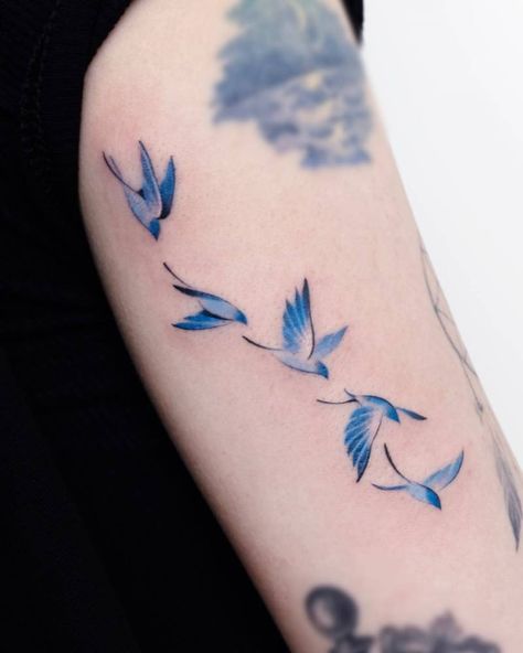 Watercolor style flying birds tattoo placed on the Dragon And Bird Tattoo, Birds Flying Tattoo Design, Flying Doves Tattoo, Watercolor Bird Flying, Birds On Shoulder Tattoo, Blue Bird Of Happiness Tattoo, Falcon Tattoo Small, Bird And Clouds Tattoo, Bird Tatoos Woman Arm