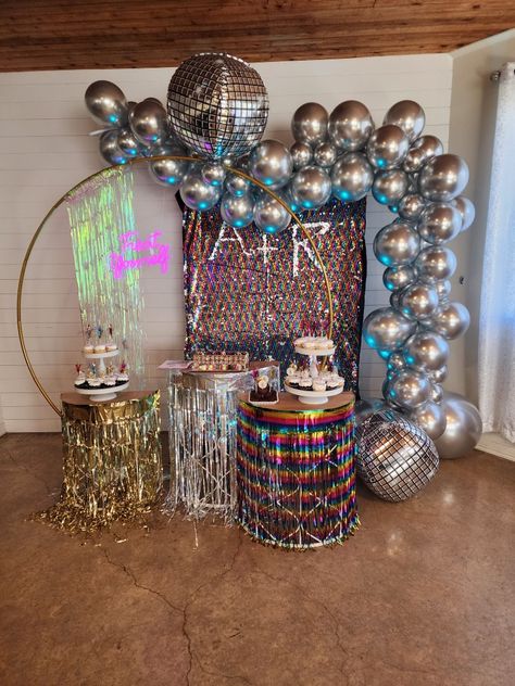 Dessert stands with chrome silver balloons and multi colored backdrop. 6ft gold round stand. Cupcakes and cake display. Through the decades themed party for adults. Disco, 70's and 80's.