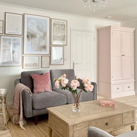 Standing in this living room, you'll notice a light pink cabinet pushed into the corner. A deep rose pillow is placed on the gray couch. You may wish to place a pink box near the bouquet of pink flowers on a light wood coffee table to add an additional pink accent. Pink Accents Living Room, Light Wood Coffee Table, Pink Living Room Ideas, Stylish Apartment Decor, Pink Cabinet, Yellow Walls Living Room, Pink Living Room Decor, Railing Designs, Grey Walls Living Room