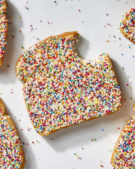 Overhead shot of a piece of fairy bread with a bite taken from the top right, on a white surface, and extra rainbow sprinkles scattered on the surface. Confetti Bread, Fairy Bread Recipe, Australian Childhood, Rainbow Bread, Rainbow Baking, Edible Confetti, Fairy Bread, Butter Bread, Ice Cream Floats