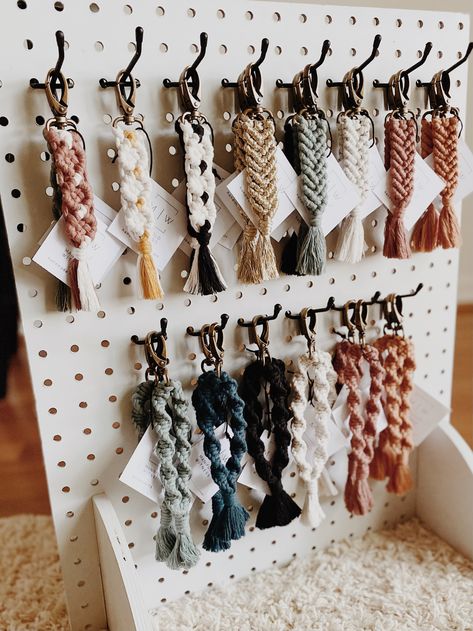 A variety of colorful macrame keychains arranged on a display board Macrame Sale Display, Pricing Display Ideas Craft Fairs, Macrame Selling Stand, Macrame Store Display, Handmade Shop Ideas, Macrame Display Booth, Macrame Craft Booth, Macrame Market Display, Macrame Work Station