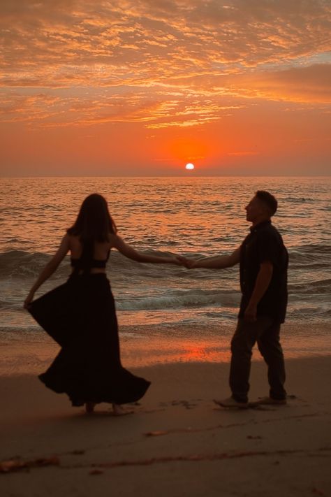 young couple dancing with the sunset to la vie en rose. girl is wearing black dress and boy is in khakis and a dark button up. The sun is setting behind them, spreading a bright orange and pink hue across the sky and into a set of clouds at the very top of the photo.the photo is taken at a beach in La Jolla San Diego California. Couples On Beach Sunset, Sari Beach Photoshoot, Sun Set Couple Photos, Beach Pictures Sunset Photo Ideas, Beach Sunset Couples Photoshoot, Sunset Photoshoot Ideas Couple, Sunset Couple Photography Beach Photo Ideas, Sunrise Photoshoot Couple, Beach Nikkah