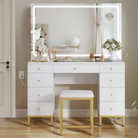 Enhance your daily beauty routine with our White and Gold Vanity Desk Set, designed in a modern style. The centerpiece of this set is a large LED lighted mirror measuring 39''x22.5'', offering a wide viewing angle for precise makeup application. With 3 adjustable color modes, you can achieve the perfect lighting for a clear and flawless look.The vanity desk features a convenient charging station with 2 standard outlets and 2 USB ports, allowing you to connect your hair dryer and charge your cell phone simultaneously. It also boasts 9 drawers, providing ample storage space for all your beauty essentials. The center drawer includes a divider for organized storage of accessories, ensuring everything is easily accessible when needed. To complete the set, we've included a stylish makeup stool. Gold And White Vanity, Bedroom Gold And White, Corner Vanity Bedroom, Vanity Ideas Bedroom Small, White Desk Bedroom, Preppy Vanity, Teen Vanity, Ikea Dressing Table, White Vanity Desk