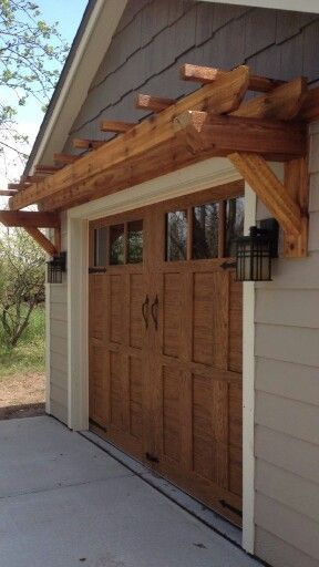 Small Pergola Over Garage Doors, Modern Pergola Above Garage Door, Mini Pergola Over Garage, Small Porch Awning Ideas, Front Door Trellis Ideas, Dress Up Garage Exterior, Exterior Window Trellis Ideas, Detached Garage Landscaping, White House Brown Roof Black Trim