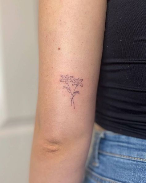 FIne line lilies tattooed on the tricep, minimalistic Closed Lily Tattoo, Lily Flower Ankle Tattoo, Mountain Lily Tattoo, Easter Lily Tattoo Small, Small Lilly Tattoo Simple, Lilly Tattoo Fine Line, Lilly Finger Tattoo, A Lily Tattoo, Minimalistic Lily Tattoo