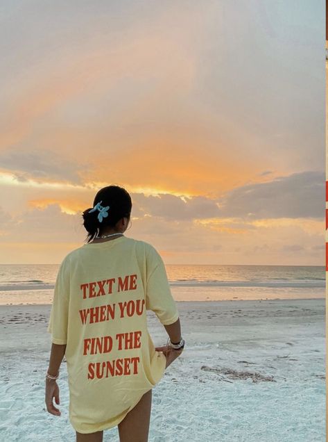 A girl watching the sunset on the beach. She’s wearing an oversized t-shirt that says “text me when you find the sunset”. Beach Outfits Asthetics, Oversized Shirt Pose Ideas, Beach Tshirt Outfit, Beach Outfit Oversized Shirt, Oversized Shirt Beach Outfit, Beach Shirts Aesthetic, Oversized T Shirt Photoshoot, Beach Vibes Clothes, Beach Tshirt Photoshoot