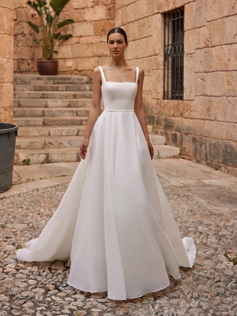 If it’s classic elegance you’re searching for, the Moonlight Tango T133 wedding dress is a luxe choice for your big day. Constructed in organza and satin fabrics that offer contrasting textures, this exquisite gown has a dreamy, ethereal look and feel that’s fitting for a black tie fairytale wedding or a more modern, minimalist event. This design boasts a sleeveless, fitted bodice in smooth satin fabric with a chic square neckline, wide straps that provide comfort and support, and a low scoop Simple A Line Wedding Dress, Square Neck Wedding Dress, Moonlight Wedding Dress, Bridal Gown Inspiration, Bodice Wedding Dress, Moonlight Bridal, Satin Fabrics, Embellished Wedding Dress, Minimalist Bride