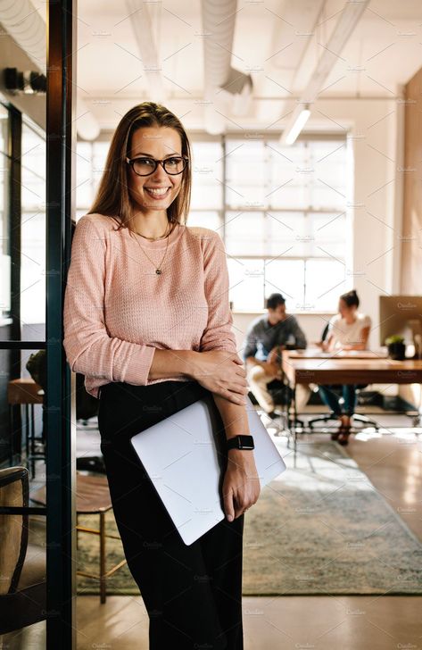 Portrait of smiling young woman leaning to office doorway holding laptop. Beautiful female executive at office with people working in background. Lifestyle photography fashion clothing stylish happy entrepreneur successful professional. #lifestyle #photography #woman #fashion #clothing #stylish #happy #entrepreneur Female Executive, Lifestyle Photography Women, Business Portraits Woman, Business Portrait Photography, Lifestyle Photography Fashion, Headshots Women, Corporate Portrait, Branding Photoshoot Inspiration, Business Photoshoot