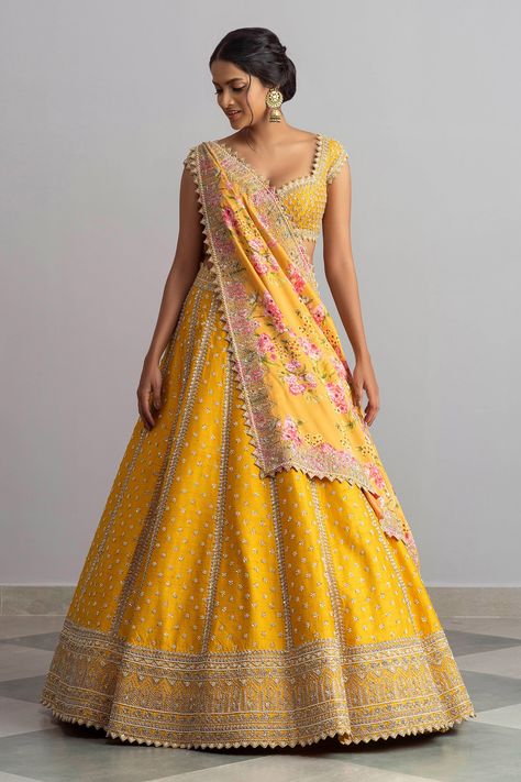 Honey yellow raw silk lehenga with cutdana work, temple border, floral motifs, striped pattern and cutwork hem. Comes with embroidered blouse and floral print silk dupatta. Components:3 Embroidered, Printed Neckline:Sweetheart Sleeve Length:Cap Fabric:Raw Silk; Dupatta: Silk Color:Yellow Plunging neck Tie-up cutout back Kamar tassels Cutwork detail  - Aza Fashions Haldi Lehenga Design For Bride, Yellow Lehanga Design, Raw Silk Lehenga Designer, Raw Silk Lehenga Wedding, Yellow Silk Lehenga, Anushree Reddy Lehenga, Lehenga Styles, Haldi Outfits, Anushree Reddy