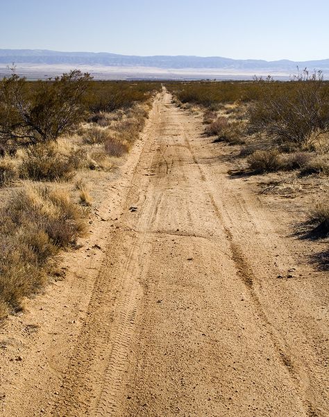 This is a desert road. Since the location of the base is in the desert, there will be areas of the ground that is worn down due to the constant movement of vehicles and humans walking, so there will be worn areas along the roads as well as the perimeter of the base from the guard patrols. Nature, Road In Desert, Pavilion Ideas, Logo Moodboard, Desert Background, Abandoned City, Desert Road, Desert Area, Dumpsters