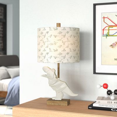 This table lamp brings a cretaceous charm to your child's bedroom with its resin t-rex base. The dinosaur stands on a wooden block and supports the wood dowel for a charming Scandinavian-inspired design. Up top, the fabric drum shade diffuses the light from the 100w bulb (not included) that sits inside. Plus, the shade is decorated with origami-inspired dinosaur drawings. A 3-way switch operates this light, so your child can choose between low or high levels of light. | Viv + Rae Horatio 27" Tab Dinosaur Table Lamp, Dinosaur Theme Nursery, Dinosaur Drawings, Dino Room, Dinosaur Kids Room, Dino Nursery, Resin Fabric, Dinosaur Light, Red Table Lamp