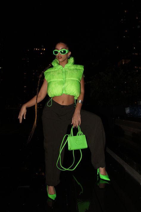 Neon puffer vest, olive green slacks, neon green pointed kitten heels, neon green mini Telfar purse, and neon green shades. Hairstyle: long, slicked braided ponytail. Black background Bariloche, Lime Green Black Outfit, Green Outfits For Women Black, Black Neon Outfit, Neon Green Heels Outfit, Neon Green Outfit Aesthetic, Neon Shirt Outfit, Purse Telfar, Neon Green And Black Outfit