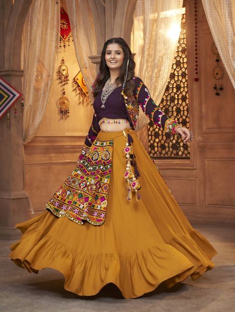 Embrace the vibrancy of Navratri with Shubhkala's Mustard Thread Embroidered Lehenga Choli Koti Set. This ensemble exudes elegance with its circular lehenga and wine-colored blouse, both crafted from luxurious Viscose Rayon. Intricate mirror work adds a touch of glamour, while the matching koti shrug completes the look. Stitched to perfection, this outfit promises to elevate your festive style effortlessly. Gujarati Chaniya Choli, Garba Chaniya Choli, Navaratri Chaniya Choli, Dandiya Dress, Garba Outfit, Navratri Lehenga, Chanya Choli, Chaniya Choli Designs, Garba Dress
