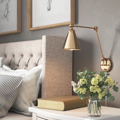 This 1-light wall sconce brings convenient light and classic style to any corner. It's made from metal with a neutral finish, and it has a cone-shaped steel shade for a vintage-inspired look. This sconce features a circular backplate with a slim linear arm that bends and turns to direct light exactly where you want it. The shade holds one standard bulb (sold separately). Whether you place this fixture in your entryway, hallway, or bedroom, it's sure to brighten your space. Finish: Gold | Three P Reading Lights Over Bed Wall Lamps, Bed Wall Lamps, Bedroom Wall Lights Beside Bed Ideas, Cottage Bedroom Wall Lights, Wall Sconces Bedroom Simple, Bedside Table Lighting Ideas, Bed Reading Lights Wall Lamps, Bedroom Wall Light Fixtures Master, Primary Bedroom Sconces