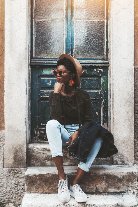 A fancy African female in stylish clothes, sunglasses, earrings, and the hat is sitting on the stone step of the porch of an old house with an antique wooden door behind, and looking aside. #lifestyle #fashion #stylish #woman #clothing #outdoors #summer Stylish Clothes, Stone Step, Fancy Girl, Street Portrait, Photoshoot Idea, Elegant Girl, Family Images, Stylish Woman, People Photos