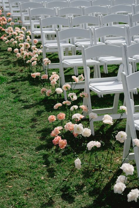 Pink and white florals lined up down the ceremony aisle with classic white chairs | ceremony details, ceremony inspo, ceremony florals, floral aisle Rose Lined Aisle Wedding, Ceremony Aisle Flowers Outdoor, Wedding Aisle Ribbon, Flowers In Ground Wedding Aisle, Single Stem Aisle, Flowers Lining The Aisle, End Of Aisle Flowers, Wedding Ceremony Set Up, Ceremony Florals On The Ground