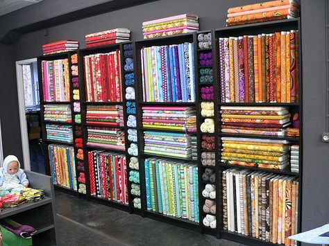 Black bookshelves for quilt shop bolt display Fabric Bolt Shelf, Fabric Shop Interior, Fabric Shop Display, Quilt Shop Displays, Fabric Store Displays, Fabric Store Design, Haberdashery Shop, Clothing Store Displays, Retail Store Interior Design