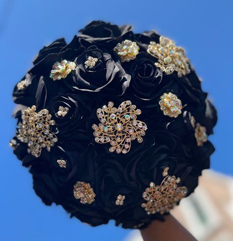 Handmade quinceañera bouquet with Black color shade of roses. Finished off with Gold brooches.  *Please note brooches can change in style based on availability*   Decor can be changed upon request.  *This is a made to order bouquet* Champagne And Black Bouquet, Rose Gold And Black Quinceanera Dress, Main Table Quinceanera Black And Gold, Black And Gold Quinceanera Centerpieces, Black Quinceanera Bouquet, Quinceanera Dresses Gold And Black, All Black Quinceanera, Black And Rose Gold Quinceanera Dress, Black Quince Bouquet