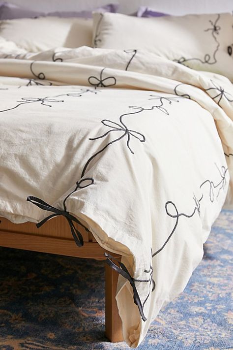 Our fave femme icon gets a chic refresh with this lightweight cotton embroidered duvet cover. Its crisp construction features textural bows stitched allover the top panel with a solid cotton panel at the reverse for a silky-soft finish. Pair it with our Lacey Bows Sham Set for a coordinated bedding set. Available exclusively at Urban Outfitters. Features Chic bow duvet cover from UO Home in crisp cotton Finished with textural bows allover the top panel Backed with a solid cotton panel Hidden button closure and internal corner ties keep your duvet insert in place An eco-friendly upgrade, this item is OEKO-TEX® Standard 100 certified free of harsh chemicals UO exclusive Content + Care Pillow shams and duvet insert sold separately 100% Cotton OEKO-TEX® Standard 100 Certified Meets OEKO-TEX® S Bow Bedding Urban Outfitters, Decorative Pillow Cheat Sheet, Cool Bedspreads, Dorm Curtains Bed, Cute Simple Bedding, Dorm Bedding Green, White Bed With Colorful Accents, Bedroom Ideas Urban Outfitters, Textured White Bedding