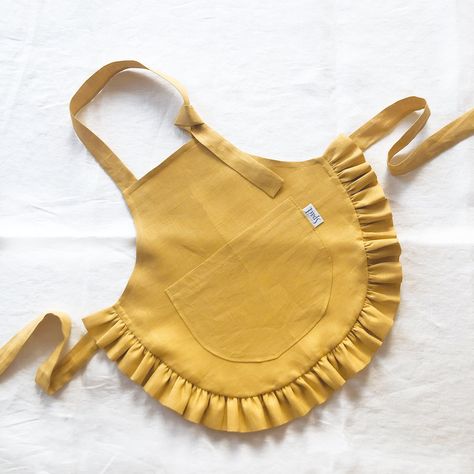 "Linen kids apron with ruffle. Ideal for cooking, gardening, painting and more. Perfect as a gift. Details: - one pocket - easy adjustable with ties Made of: - 100% European linen fabric Oeko-Tex certified linen Color: - Mustard - more colors will be available soon Sizes: - 2-4 years: 48x42 cm / 18.9x16.5\" - ties length 50 cm / 19.7\" - 4-7 years: 55x48 cm / 21.6x18.9\" - ties length 50 cm / 19.7\" - 7-10 years: 62x54 cm / 24.4x21.3\" - ties length 60 cm / 23.6\" Care instruction: - machine was Tela, Gardening Painting, Child Apron Pattern, Baby Bumper, Toddler Apron, Linen Pinafore, Girl Apron, Sewing Aprons, Bib Apron