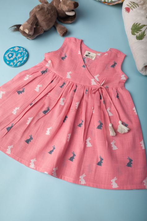This baby pink kids cotton slub frock is a charming and cute choice for any child’s wardrobe. It features handmade tassels on the side, which adds a playful and unique touch to the design. The frock also has an adorable rabbit print, which is sure to delight any child. The frock has an angrakha neck, which is a traditional and elegant style that adds sophistication to the design. With a sleeveless design, this frock is perfect for warm weather and outdoor play. Made from soft and comfortable cot Couture, Baby Girl Frock Designs Parties, Frok Designs, Baby Cotton Dress, Cotton Frocks For Kids, Frocks For Babies, Frocks For Kids, Baby Clothes Patterns Sewing, Kids Dress Collection