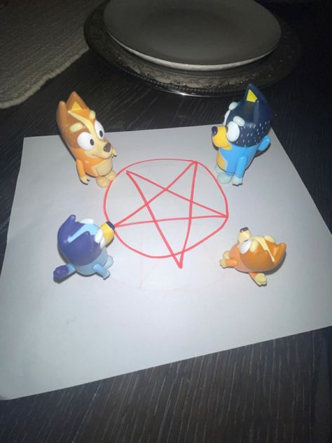 The main characters from the Disney JR show Bluey standing around a pentagram
