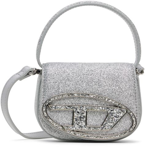 Find Diesel Silver 1dr-xs-s Bag on Editorialist. Glittered faux-leather top handle bag in silver-tone. · Carry handle · Adjustable and detachable crossbody strap · Logo hardware at face · Magnetic press-stud flap · Logo-woven twill lining · H4 x W5 x D2 Supplier color: Silver Diesel Bags, Diesel Bag, Diesel Tops, Faux Leather Top, Silver Bags, Silver Tops, Travel Gear, Press Studs, Handle Bag