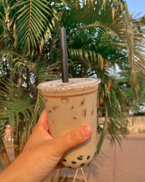 bubble tea being hold by a left hand with a palm tree in the background Boba Tea Aesthetic Pictures, Boba Tea Shop Aesthetic, Milk Tea Picture, Bubble Tea Aesthetic Instagram, Tapioca Aesthetic, Instagram Feed Pictures, Boba Milk Tea Aesthetic, Bubble Tea Photo, Tea Food Photography