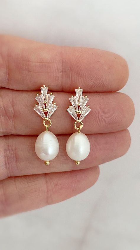 Our Ariana gold freshwater Pearl drop bridal earrings are simply stunning! These dainty pearl drop earrings catch the light, packing serious sparkle for their size. Combining marquise crystals stones they're finished with glowing Freshwater pearls. With just the right amount of sparkle, this dainty pair is perfect for brides, mother of the bride and bridesmaids alike. These Crystal and pearl wedding earrings will add a flawless finish to every special occasion. SHOP MORE STYLES  https://www.etsy.com/ie/shop/BridalStar?ref=related&listing_id=768478002#  Delivery is 3 weeks  *RETURNS-  We accept returns minus shipping cost ** Wedding Earring Ideas For Bride, Unique Wedding Earrings Brides, Earrings For Brides, Wedding Day Accessories Brides, Wedding Earrings Bride Gold, Silver Wedding Earrings, Pearl Wedding Details, Dangle Pearl Earrings Wedding, Wedding Jewelry Ideas For Bride
