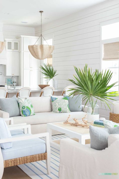 A coastal living room with linen sofas, blue and white striped rug, raffia coffee table and rope chandelier. Accented with blue and green decor. The shiplap walls are painted Sherwin Williams Snowbound. Carriage House Apartments, Spring Living Room, Spring Bedroom, Coastal Living Rooms, Coastal Living Room, Loft Spaces, Indoor Outdoor Living, Florida Home, Spring Home