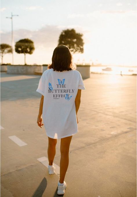 Girl wearing oversized white tshirt in parking lot with setting sun. Tshirt printed with "the Butterfly Effect of Kindness" on back in black text. Print has 3 blue butterflies around wording. Bag Poster, Forever Chasing Sunsets, Womens Christian Shirts, Boho Style Design, Gift Aesthetic, Chasing Sunsets, Y2k Shirt, Preppy Clothes, Soli Deo Gloria