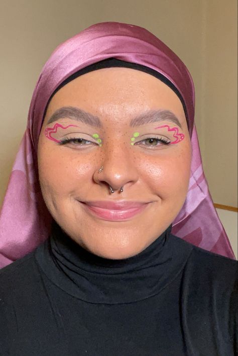 Girl wearing a pink head scarf with pink and green graphic eyeliner Neon Green And Pink Makeup, Pink Neon Eyeliner, Pink And Green Graphic Liner, Green Eyeliner Graphic, Green And Pink Eyeliner, Pink And White Graphic Liner, Spring Eyeliner Looks, Pink And Green Eyeliner, Fun Liner Looks