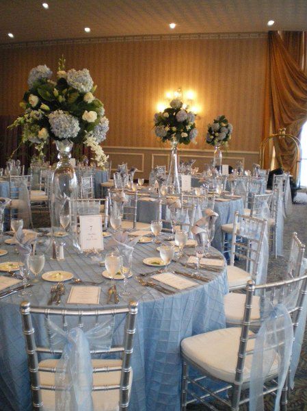 light blue wedding theme- light blue table linens, blue accents in the flower centerpieces, and light blue tulle on silver chairs Sky Blue And Silver Wedding, Blue And Silver Wedding Decorations, Cinderella Quince, Blue Quinceanera Theme, Quinceanera Blue, Baby Blue Quinceanera, Ice Blue Weddings, Light Blue Quince, Cinderella Quinceanera Themes