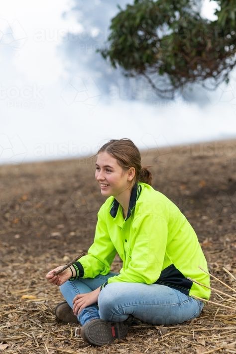 Young woman in hi-vis sitting on the ground with smoky background : Austockphoto Person Sitting On Ground Reference, Person On Ground Reference, Drawing Poses Sitting On The Ground, Person Sitting On Ground, Sitting On The Ground Pose, Sitting On Ground Reference, Sitting On Ground Poses, Comic Poses, Sitting On Ground