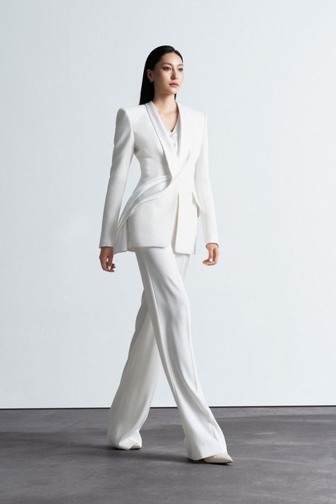 Single-breasted, slim-fit suit with 1 button at the front. It features a shawl collar with a crisscross design, fixed pleated lapels, creating a seamlessly flowing curve from the back through the collar to the front, adding a unique focal point to the neckline. The suit has a long, body-hugging silhouette, closely following the waistline. The sleeves are of a 2-button, half-length style. Two diagonal flap pockets are present on the body. The gilet portion is seamlessly integrated with the vest and has a row of 4 buttons. Recommend using a steam washing machine for LE KIEU's clothes. First, examine the washing symbols on the product tags to ensure compatibility. Avoid direct contact between detergent and clothes. Hand wash or dry clean wool, silk, chiffon, and beaded clothes. For silk, broc Clothes Crafts, Beaded Clothes, Washing Symbols, Japanese Crepe, Japanese Crepes, Product Tags, White Suits, Gifts For New Mums, Women's Wardrobe