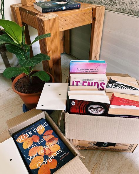Books in moving boxes, surrounded with plants and tables Moving In Aesthetic Boxes, Moving House Aesthetic Boxes, Moving Box Aesthetic, Moving To A New City Aesthetic, Vision Board Moving Out, Move In Day Aesthetic, The Right Move Aesthetic, Move Out Aesthetic, Moving Aesthetic Boxes
