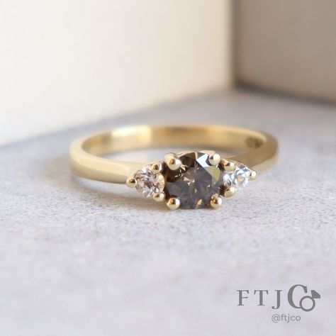 This espresso-hued diamond (!) goes out to all the coffee lovers... ☕️ Have you ever seen a diamond ring like this before? The rich warm brown diamond is paired with two white sapphires, and our buttery 18K yellow gold, making an absolutely scrumptious engagement ring. What's more, these stones are lab grown! Some folks assume lab grown diamonds are all colourless and cookie cutter, but we seek out the most interesting ones, which you can find in our Unique Gems collection on our site! 💎🔍👀 . ... Coffee Lovers, Brown Engagement Rings, Brown Diamond Engagement Ring, Brown Diamond Ring, Brown Diamond, Warm Brown, The Rich, White Sapphire, The Coffee